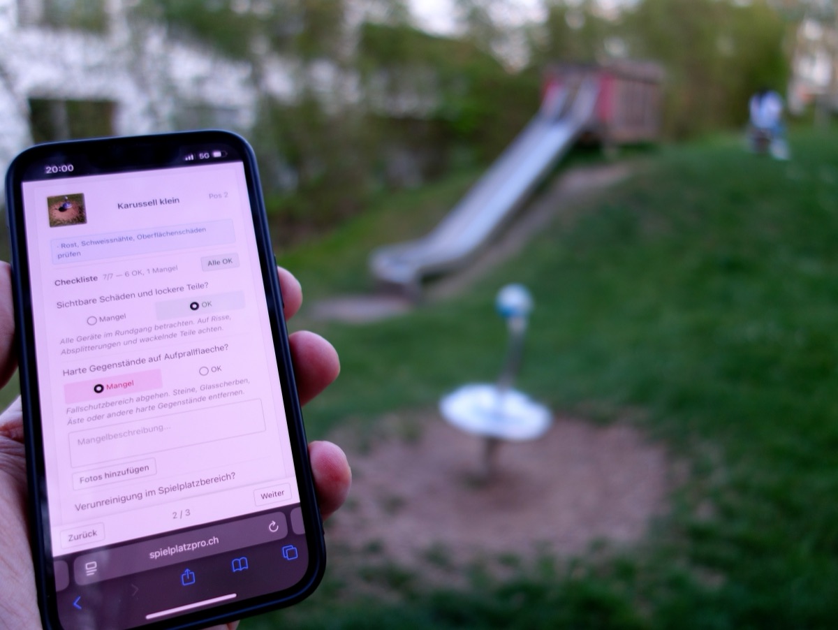 SpielplatzPro Checkliste auf einem Smartphone, im Hintergrund ein Spielplatz mit Rutsche